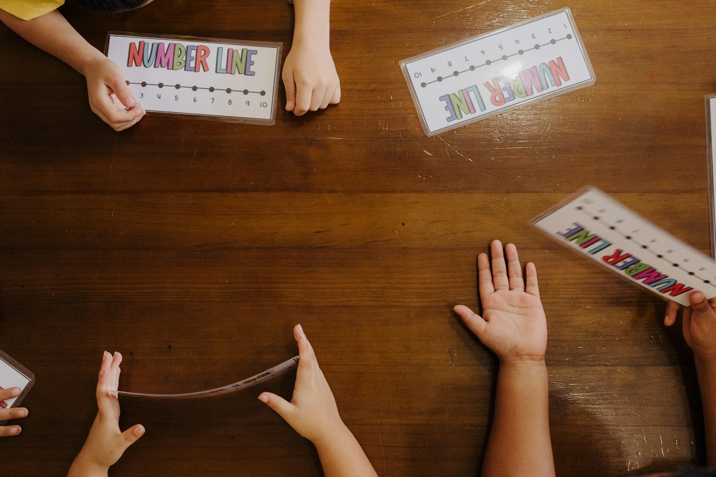 Manos de niños jugando con tarjetas de números en una mesa.